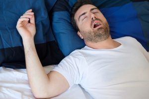 Man sleeping on his back with mouth open, snoring.