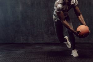 Man in sportswear holding a basketball while training indoors.