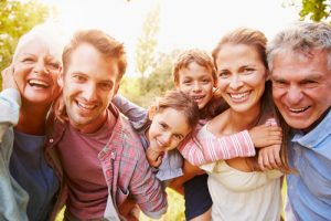Happy multi-generational family smiling outdoors together on a sunny day.