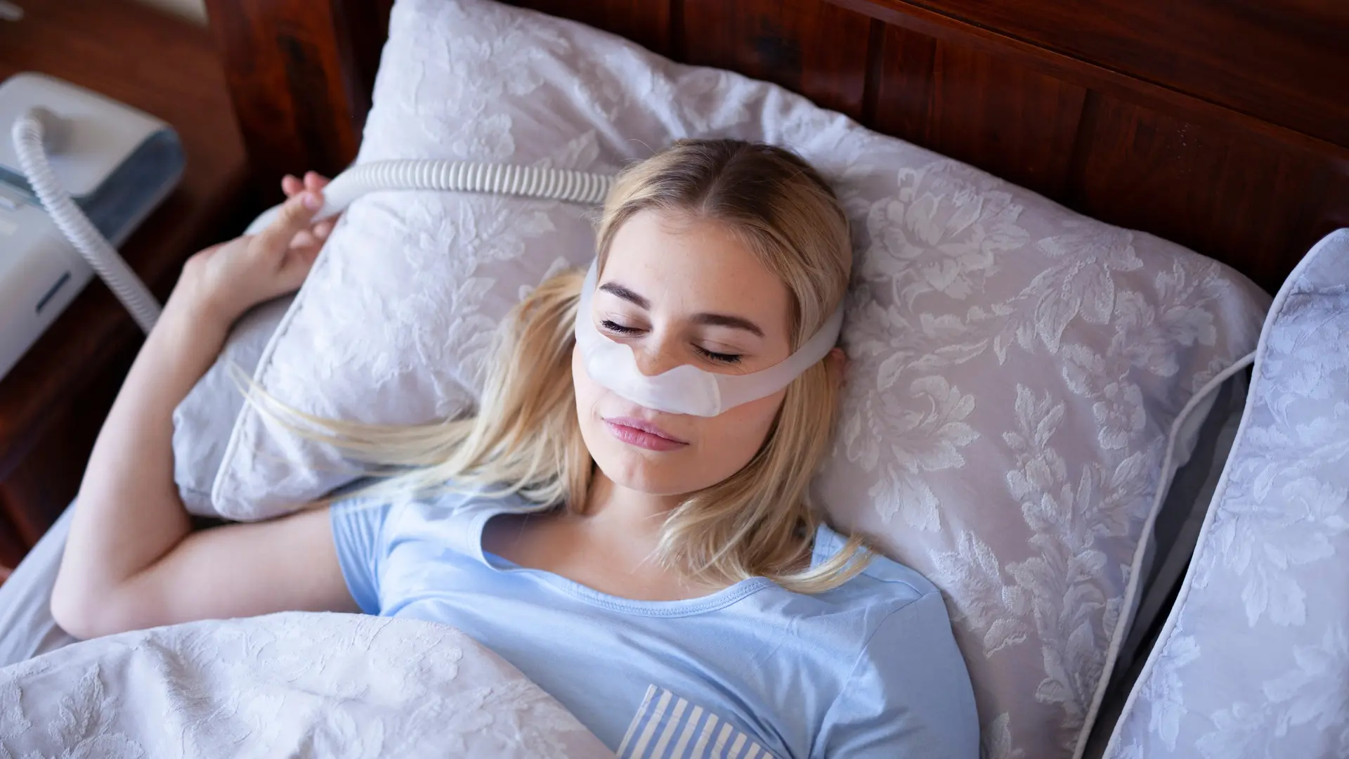 Person wearing CPAP mask while sleeping for sleep apnea treatment.