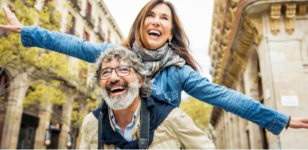 Happy senior couple enjoying a piggyback ride outdoors, smiling and carefree.