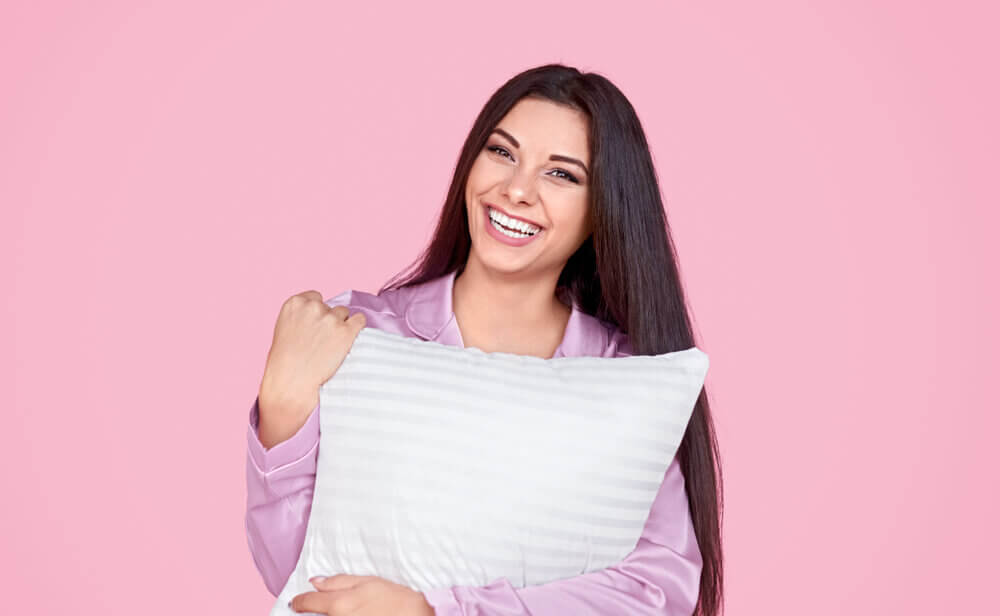woman smiling while hugging her pillow