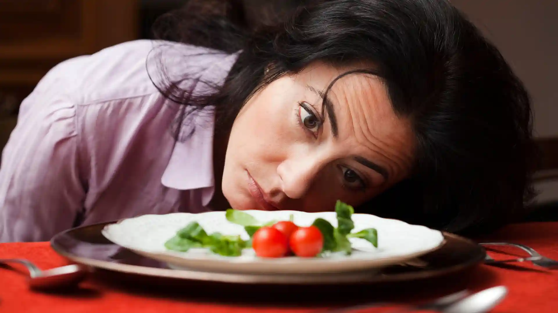 a woman staring at a plate with vegetable