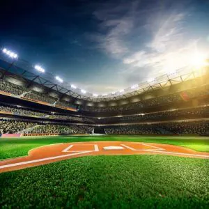 Baseball stadium under bright lights with home plate in the foreground and a crowd in the stands