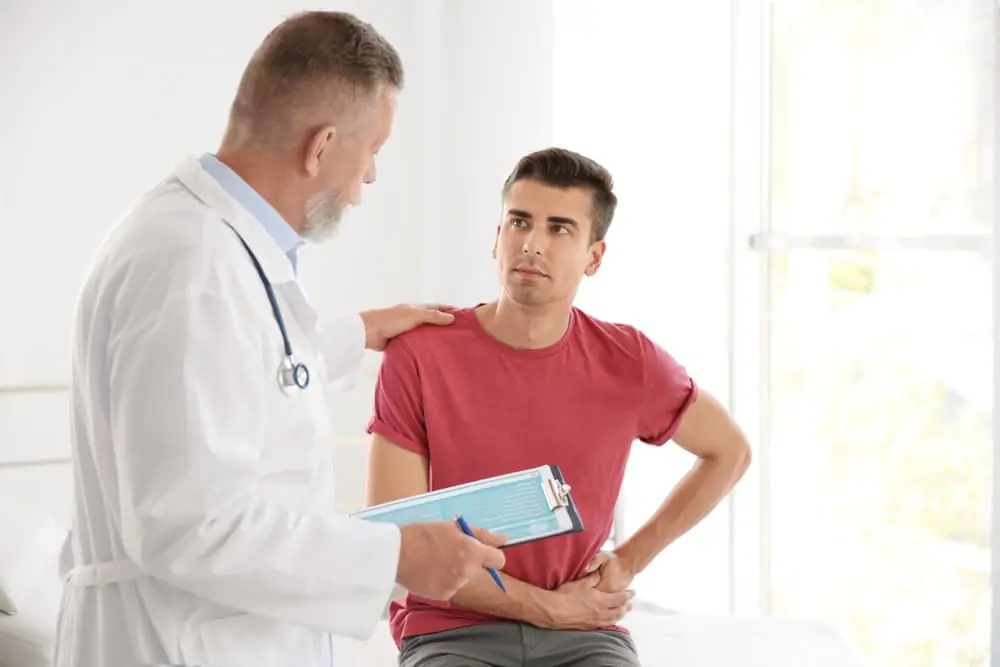 Male patient with hip pain consulting a doctor during medical examination.